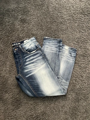 Blå slitna jeans från Denham - Säljer ett par blå jeans från Denham med slitningar och snyggt tvättad look. Jeansen har raka ben, klassisk femficksmodell och detaljerade slitningar vid knäna. Perfekta för en avslappnad och trendig stil. Storlek W31 L30 men sitter som W30 L32  