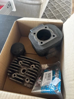 Polini Corsa 70cc Yamaha Slider - Säljer ett cylinderkit till moped som innehåller cylinder, topplock, kolv och packningssats. Delarna är i metall och har en mörkgrå färg. Perfekt för dig som vill trimma eller byta ut delar på din moppe.
