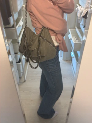 Grön Stella McCartney handväska - Cool grön handväska från Stella McCartney med kedjedetaljer i silver och mjukt material. Väskan har en avslappnad form och axelrem i kraftig kedja. Perfekt för dig som gillar trendiga accessoarer och vill sticka ut med en snygg designerbag. Säljer billigt då jag vill bli av med den❤️