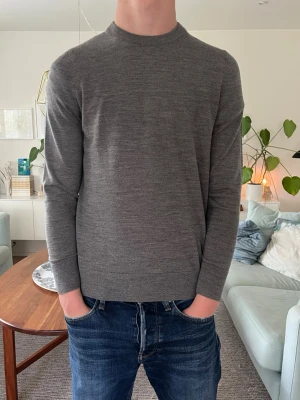 NY STICKAD TRÖJA ARKET  - En stilren grå stickad tröja med rund hals i 100% ull. Perfekt att bära till jeans eller chinos för en enkel och snygg look. Köpt för 690:-