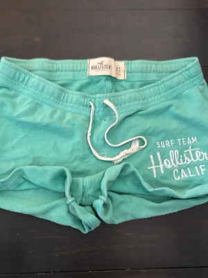Turkosa Hollister shorts - Trendiga turkosa shorts från Hollister med vit snörning i midjan och Hollister tryck på ena benet. Snygg turkos färg perfekt till sommaren. Godkänner prisförslag vid snabb affär!💕