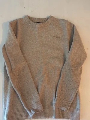 Beige stickad tröja från Barbour - Klassisk beige stickad tröja från bondelid med rund halsringning och diskret bondelid logga på bröstet. Tröjan har ribbade muddar vid ärmslut och nederkant. Perfekt för lager-på-lager och enkel att matcha. Storlek M men passar mycket bättre som S. Priset är ej dikuterbart eftersom jag vill bara bli av med den så snabbt som möjligt.