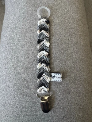 Virkad napphållare - Virkad, flerfärgad napphållare i svart/grått. Virkad av mig i 100% bomullsgarn med metallclip och silikonring.  Mönsterskapare: animo.design