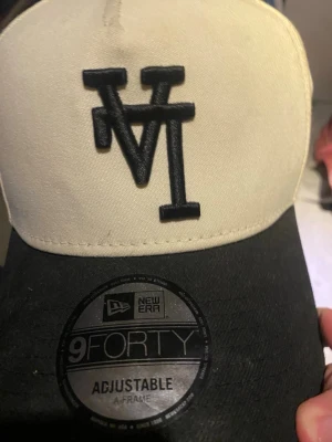 Svart och vit keps New Era 9FORTY - Snygg keps från New Era, modell 9FORTY, med svart skärm och vit frontpanel. Justerbar passform och broderad svart logga framtill. Klassisk basebollstil med A-frame och bekvämt material.