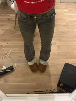 Grå bootcut jeans med låg midja - Säljer ett par gråa bootcut jeans med låg midja med femfick design. Jeansen har en lätt tvättad och har två knappar. Säljer pga för små/korta. Dem är uppsprättade vid båda benen💕