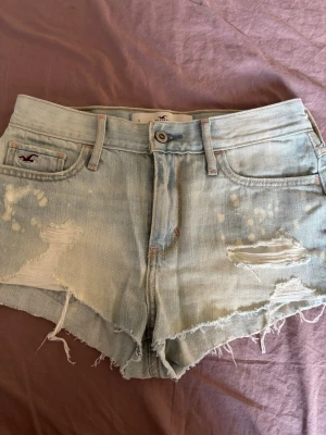 Ljusblå slitna jeansshorts Hollister - Snygga ljusblå jeansshorts från Hollister med slitna detaljer, och hål. Assnygga till sommaren och jättebra skick!