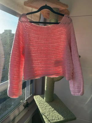 Handvirkad ljusrosa  tröja - Säljer en handvirkad ljusrosa  tröja med bred halsringning och långa ärmar. Tröjan är gjord i ett mjukt akrylgarn. Onesize men uppskattar till en L