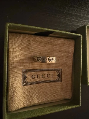 Gucci skull silverring med GG-logga - Snygg ring från Gucci i silver med klassiska GG-loggor runt om hela ringen. Ringen har en stilren och tidlös design, perfekt för dig som gillar exklusiva accessoarer med ikonisk känsla. Levereras i originalask med tygpåse.