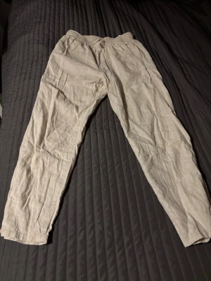 Beiga linnebyxor med resårmidja - Säljer ett par ljusbeige linnebyxor med avslappnad passform och resår i midjan. Byxorna har raka ben och en enkel, stilren look som passar perfekt till sommaren. Materialet är svalt och luftigt linne, vilket gör dem riktigt sköna att bära.