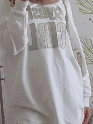Vit hoodie med glittertext GIRL - Säljer en oversized vit hoodie med stora glittriga bokstäver där det står GIRL på framsidan. Hoodien har långa ärmar och en avslappnad passform, perfekt för en chill och trendig look.