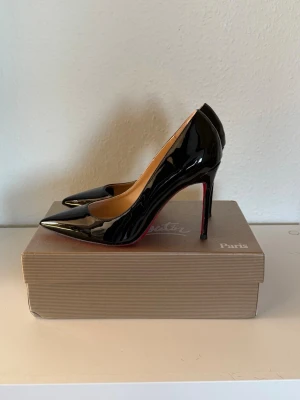 Svarta lackpumps från Christian Louboutin - Snygga svarta pumps i lack från Christian Louboutin med klassisk spetsig tå och höga stilettklackar. Skorna har den ikoniska röda sulan och en elegant, tidlös design som passar perfekt till alla tillfällen.