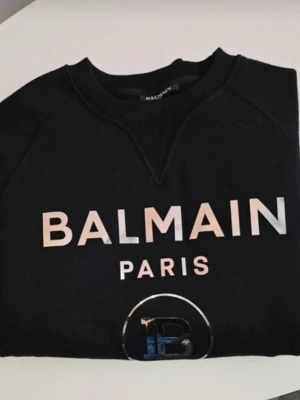 Svart Balmain Paris hoodie - Snygg svart orginal hoodie från Balmain Paris med stort tryck i silver framtill. Testad någon enstaka gång så som jelt ny 