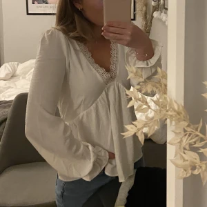 Vit långärmad blus - Vit långärmad blus med V-ringning och spetsdetalj. I strl XS från Vero Moda. Använd fåtal gånger! 