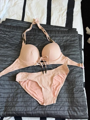 Ljusrosa bikini med knyt och vaddering - Snygg ljusrosa bikini med vadderad bygel-bh och knyt i nacken samt framtill. Bikinitrosan har klassisk passform och samma mjuka material. Perfekt för stranden eller poolen!Storlek på övre delen 75D och på nedre delen M