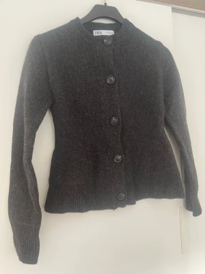 Mörkgrå kofta från Zara - Mysig mörkgrå kofta från Zara, koftan är något figursydd och är därför väldigt fin på. Strl s, endast använd ett par tillfällen