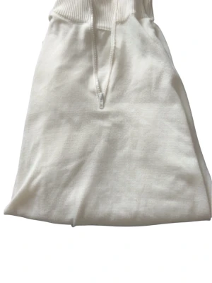 Vit hoodie med halv dragkedja - Snygg vit hoodie med halv dragkedja framtill och ribbade muddar vid ärmslut och midja. Hoodien har en klassisk passform och är tillverkad i mjukt material som känns skönt mot huden. Perfekt för en clean och enkel look.