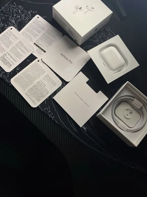 Apple AirPods Pro med laddningsetui - Säljer ett par Apple AirPods Pro med trådlöst laddningsetui. Hörlurarna är vita, har en stilren och kompakt design och levereras med originalkartong, laddningskabel och manualer. Perfekta för dig som vill ha grymt ljud och brusreducering.
