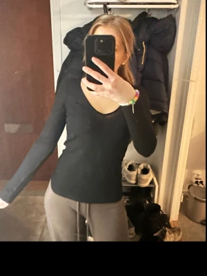 Svart långärmad v-ringad topp - En enkel och stilren svart långärmad topp med v-ringning. Perfekt basplagg som är lätt att matcha med olika outfits. Sitter normal mot kroppen och har en mjuk känsla.