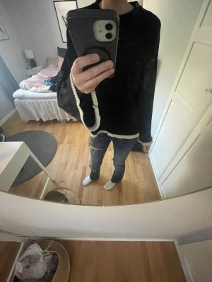 Svart stickad tröja med vita detaljer - En svart stickad tröja med vita ribbade kanter vid ärmslut och nederkant. Säljer då jag inte använt på ett tag. Pris kan diskuteras😊😊