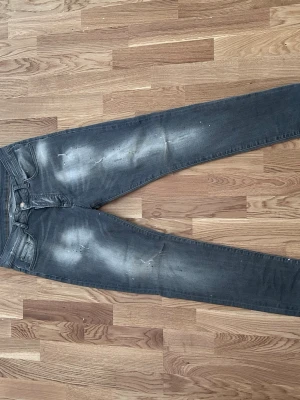 Dsquared2 - Säljer ett par grå skinny jeans med slitningar och blekta detaljer på framsidan. Klassisk femficksmodell med dragkedja och knapp. Jeansen har en smal passform och är perfekta för en avslappnad streetstil.