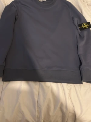 Blå stickad tröja  - Säljer en blå stickad tröja med klassisk rund hals och ribbade muddar. på vänster ärm och är tillverkad i mjukt material som passar perfekt för en avslappnad look.