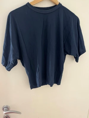 Mörkblå croppad t-shirt - En enkel och stilren mörkblå croppad t-shirt med rund hals och korta ärmar. Perfekt till jeans eller kjol för en avslappnad look. Tillverkad i mjuk bomull som känns skön mot huden.