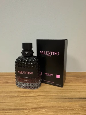 Valentino Uomo Born In Roma Intense - Valentino Uomo Born In Roma Intense är en lyxig parfym med en cool, mörk glasflaska täckt av nitar och detaljer i svart och rosa. Flaskan har en unik, edgy design och kommer i en snygg svart kartong med rosa text. Perfekt för dig som vill sticka ut med en exklusiv doft.