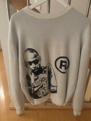 Vit stickad tröja med tryck - Vit stickad tröja med svart grafiskt tryck av Thiery Henry och ett stort R-märke på framsidan. Rund halsringning med ribbstickade muddar. Märkeslapp med fotbollsgrafik och texten 'The Beautiful Game' i nacken. Ny pris 899