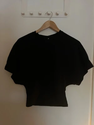 T-shirt från Nelly  - Populär svart T-shirt från Nelly, som är tajt i midjan och har stora ärmar. Använd två gånger. Storlek xs. 💕