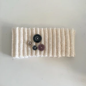 Virkad vit öronvärmare  - Handvirkad vit öronvärmare med fina knappar på. Perfekt nu på vintern❄️ virkad med bomullsgarn. Mått: bredd: 21 cm längd: 9cm ✨ Skriv om ni har fler frågor!