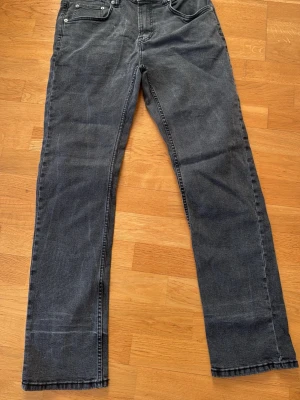 Grå slim fit jeans från 157 - Säljer ett par grå slim fit jeans från 157 med klassisk femficksmodell och raka ben. Jeansen har silverfärgade detaljer och bälteshällor. Perfekta för dig som gillar en enkel och stilren look.
