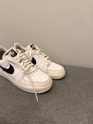 Nike Air Force 1 vita sneakers - Klassiska Nike Air Force 1 sneakers i vitt läder med svart swoosh på sidorna. Skorna har använd i knappt 3 veckor.  Pris kan diskuteras eller om du har frågor hör av dig.