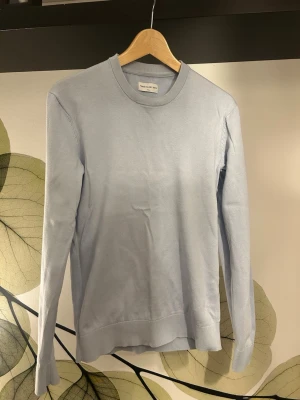 Ljusblå These Glory Days tröja från VOLT Fashion - En stilren ljusblå tröja från VOLT Fashion i mjukt material. Tröjan har rund halsringning, långa ärmar och ribbade muddar vid ärmslut och nederkant. Perfekt för dig som gillar minimalistisk och clean stil.