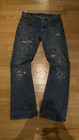 Lee bootcut - Säljer dessa Lee-jeans eftersom de är för små för mig. Jeansen har lagad/sliten (distressed) design samt lite mindre slitage vid hälen och ett litet hål i yttersömmen vid höfterna.  Modellen är Denver cut och jeansen sitter tajt över höfterna med en stor utsvängning som börjar vid knäet.  Priset är förhandlingsbart och det är bara att ställa frågor om plagget. Priset är inte hugget i sten så kom gärna med bud!!