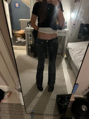 Mörkblå bootcut jeans med vita sömmar - Säljer ett par mörkblå bootcut jeans med tydliga vita kontrastsömmar och låg midja. Jeansen har klassiska fickor fram och bak samt en snygg passform som framhäver benen. Perfekta för dig som gillar en retro och avslappnad stil.