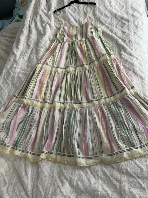 Färglagd Randig långklänning i pastellfärger, XL - Färglagd Randig långklänning i pastellfärger, XL, Mango, ,bomull. Långklänning med tunna axelband och volangdetaljer. Klänningen har ett randigt mönster i vitt, rosa, grön och gul. Tillverkad i ett lätt material som känns perfekt för sommaren. Passformen är loose och modellen är ärmlös.