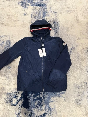 Blå Moncler Windbreaker  - Storlek S. Han på bild är 170. Nfc Scan funkar. Helt ny med tags. Pris kan diskuteras vid snabb affär!