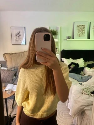 Gul stickad topp med kort ärm - Säljer en ljusgul stickad topp med korta ärmar och avslappnad passform. Tröjan har ribbad kant nedtill och är perfekt för vår och sommar. Materialet känns mjukt och luftigt. Aldrig använd!❤️