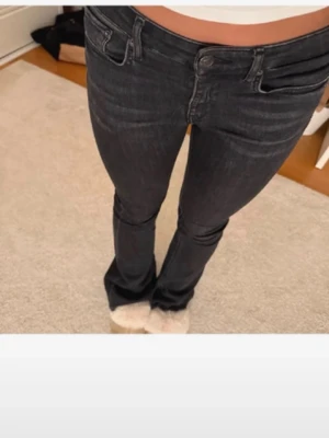 Mörkgrå bootcut jeans - Snygga mörkblå bootcut jeans med klassisk femficksdesign och normalhög midja. Jeansen har en smal passform upptill och lätt utsvängda ben. Perfekta för dig som gillar en tidlös och trendig look.