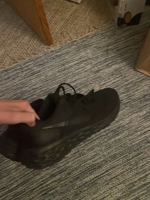 Helvita Nike sneakers mesh - Snygga helsvarta sneakers från Nike med mesh-ovandel och klassisk swoosh på sidan. Skorna har lågt skaft, snörning och en chunky sula som ger grym streetkänsla. Perfekta för dig som vill ha en clean och sportig look.