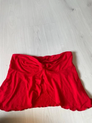 Röd kort topp med knyt från SHEIN - Säljer en röd kort topp från SHEIN med snygg knyt-detalj framtill. toppen har en mjuk och stretchig känsla, perfekt för dig som vill ha något bekvämt men ändå trendigt. Passar till många olika stilar och är enkel att matcha.