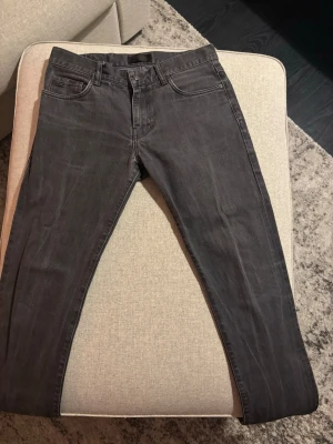 Mörkgrå slim fit jeans från J.Lindeberg - Snygga mörkgrå jeans från J.Lindeberg i slim fit-modell med klassisk femficksdesign och raka ben. Jeansen har diskreta sömmar och bälteshällor. Perfekta för dig som gillar en stilren och enkel look. Storlek 31/32