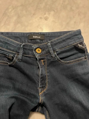 Mörkblå jeans från Replay - Snygga mörkblå jeans från Replay med klassisk femficksmodell och kontrastsömmar. Jeansen har guldfärgad knapp och diskreta broderier på bakfickorna. Materialet är denim med lite stretch för skön passform. Byxorna är i nyskick! Kan diskutera pris inom snabb affär.