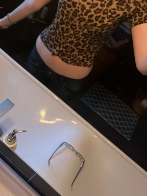 Leopardmönstrad croppad topp - Snygg croppad topp med leopardmönster i beige och svart. Toppen har korta ärmar och en tight passform som framhäver midjan. Perfekt för dig som vill sticka ut med en trendig och djurinspirerad look.