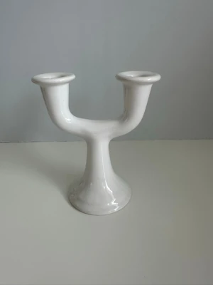 Vit keramik ljusstake med två armar - Säljer en stilren vit ljusstake i keramik med två armar. Den har en modern, rundad form och plats för två ljus. Perfekt som dekoration på bordet eller i fönstret. Passar dig som gillar minimalistisk inredning. Mycket gott skick, som ny. 