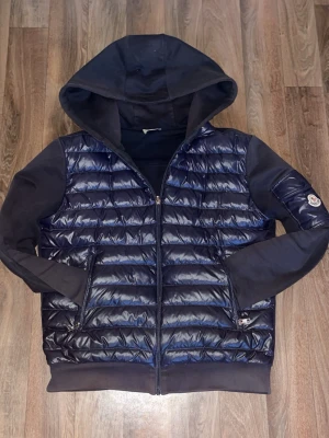 Moncler Cardigan - En go moncler cardigan på storlek S, skit fet enligt mig, helt äkta och perfekt nu inför sommaren då det är hoodie material på ryggen o väst material på framsidan. 