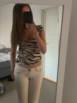 Zebramönstrad topp  - Snygg zebramönstrad topp i brun och beige med v-ringning och korta ärmar. Toppen har en figurnära passform och är tillverkad i ett mjukt, stretchigt material som känns skönt.