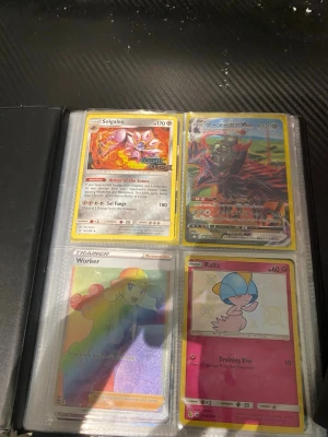 Pokémonkort i samlarpärm - Säljer ett gäng Pokémonkort i en samlarpärm. Bland korten finns Solgaleo, Worker, Ralts, Hisuian Decidueye V, och fler, både på engelska och japanska. Flera kort har holografisk effekt och färgstarka illustrationer. Perfekt för dig som gillar Pokémon och vill utöka din samling.