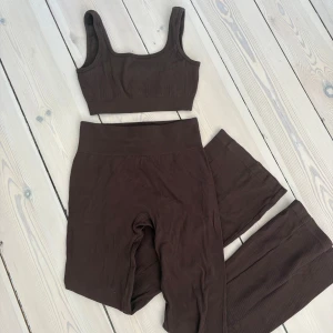 Brunt ribbat set med topp och tights - Säljer ett brunt ribbat set med en croppad topp och yogapants. Toppen har inga inlägg men man kan enkelt lägga in egna om de önskas! Superskönt material!🤎🧸