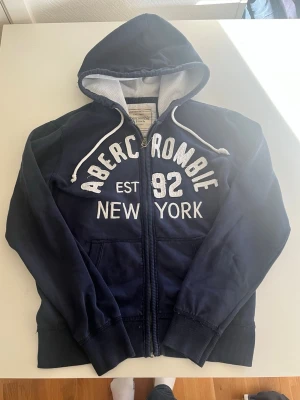 Abercrombie & fitch mörkblå zip hoodie - Riktigt snygg Abercrombie & fitch zip hoodie i mörkblå färg. Fint skick inga fel storlekM pris endast 468 kr kom gärna med frågor och prisförslag mer i min profil rabatt vid flera 😁✌️